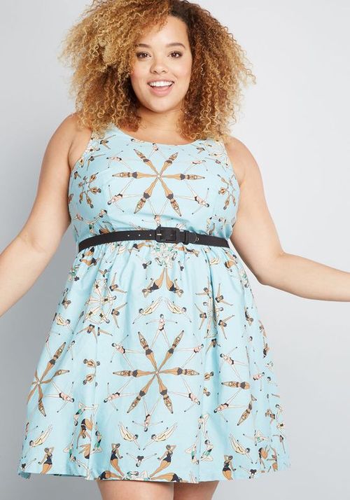 Woman wearing a light blue dress with a pattern of birds on a plain background